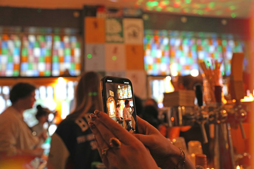 A person using a smartphone to photograph the interior of a bar