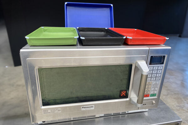 MicroSave smaller Teflon-coated tray range in four colours on a microwave; each option supplies one tray and the oven is not included